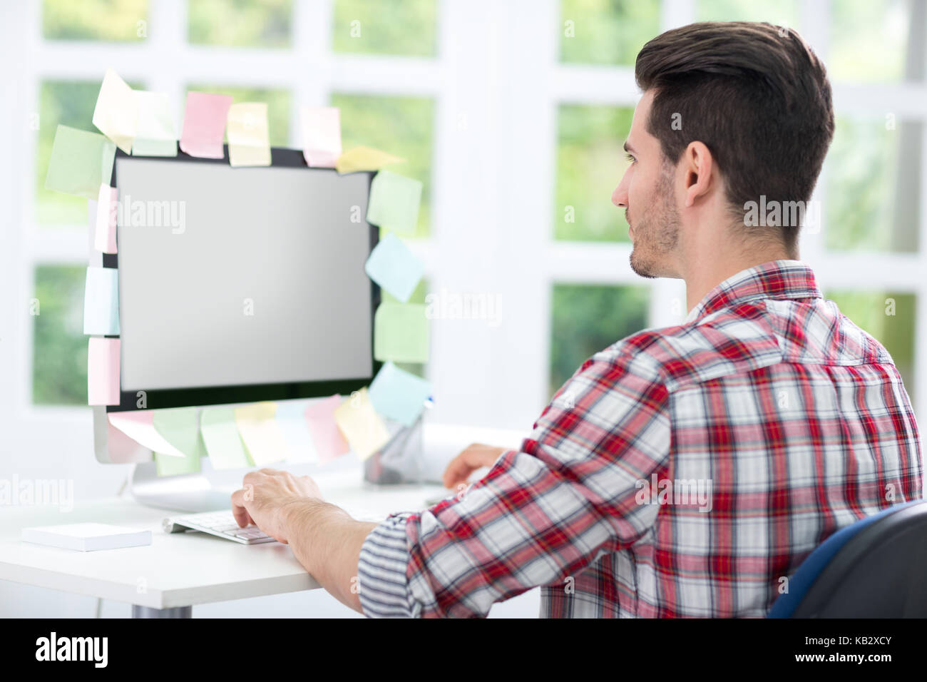 Man looking at a computer monitor with sticky note on it Stock Photo
