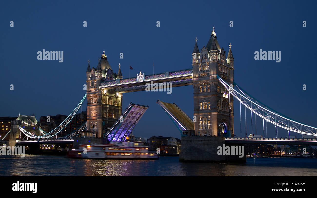 Tower Bridge at night open with boat passing through in London, England, UK Stock Photo
