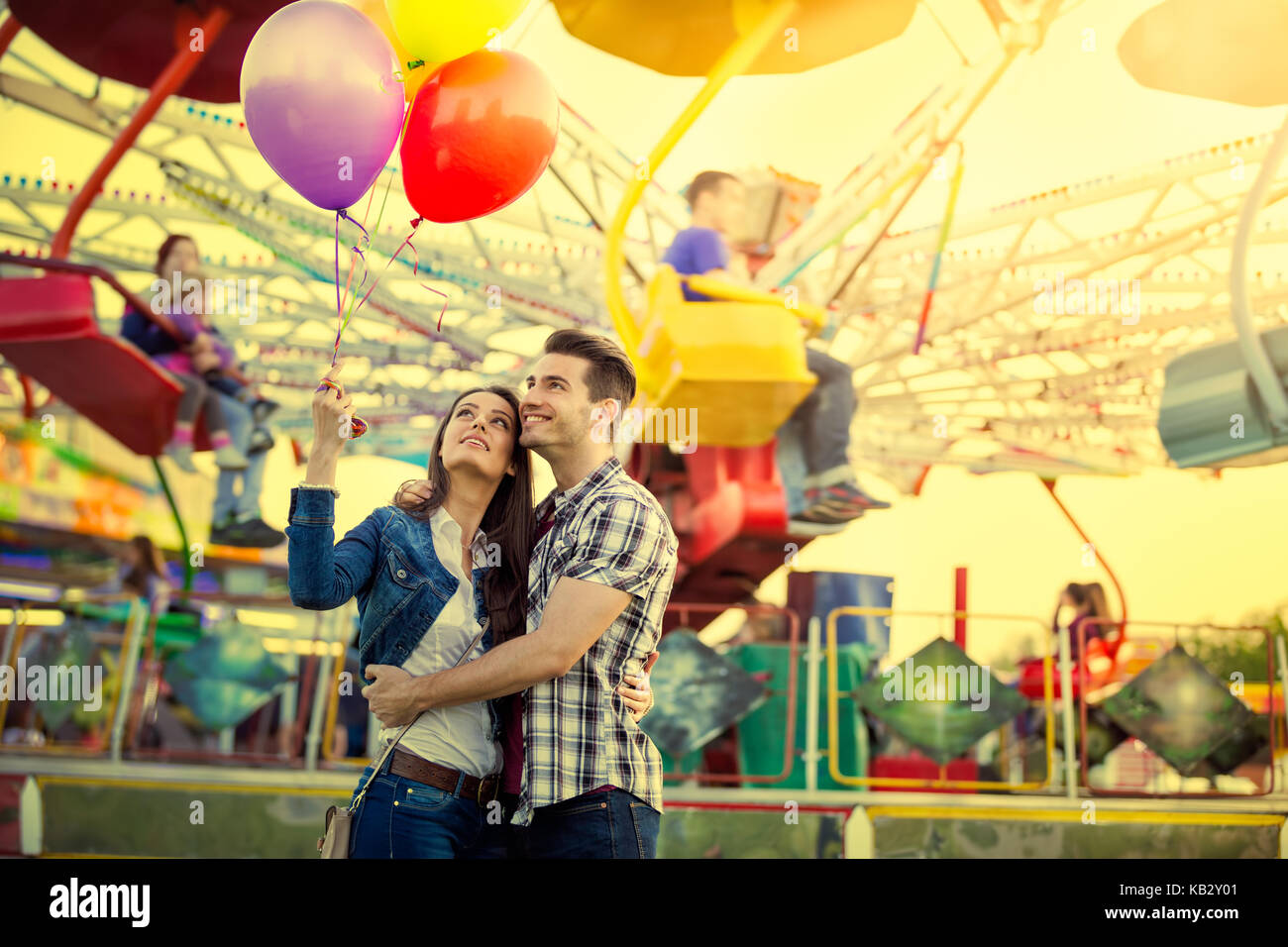 Young couple hugging and holding each other in amusement park while ...