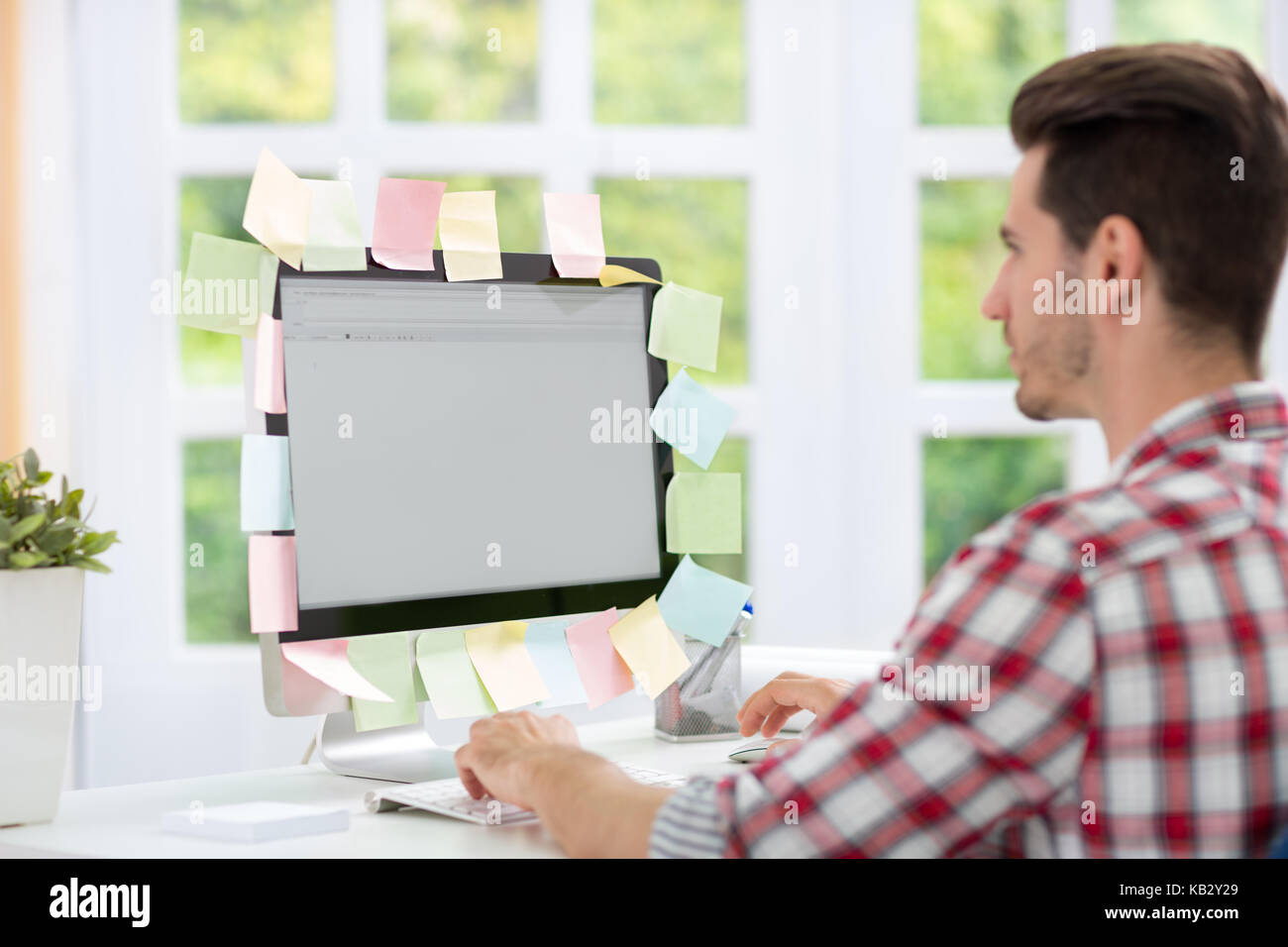Man looking at a computer monitor with notes on it Stock Photo