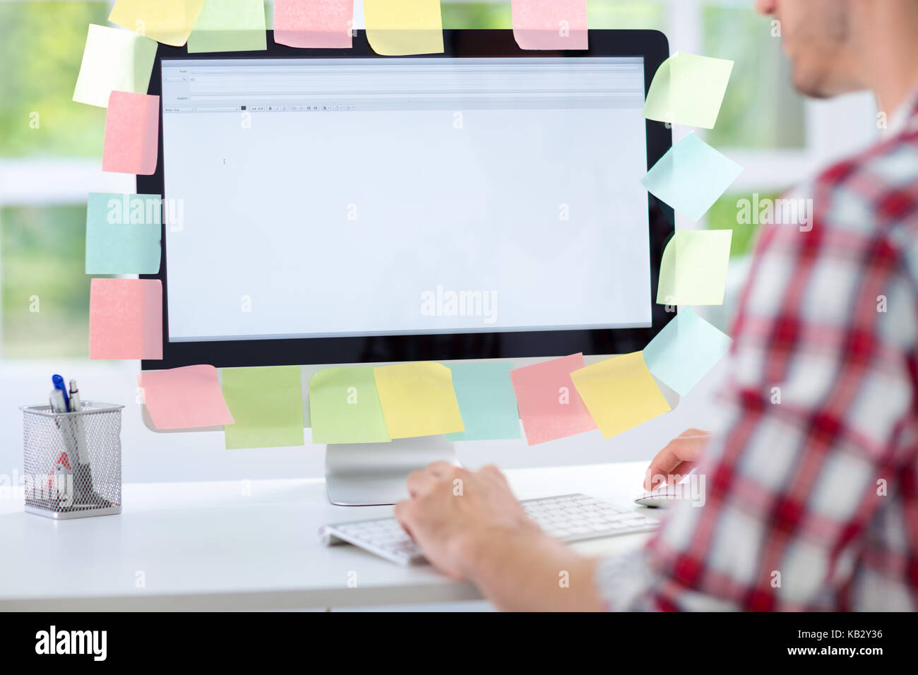 Man working on computer with sticky notes, back view Stock Photo