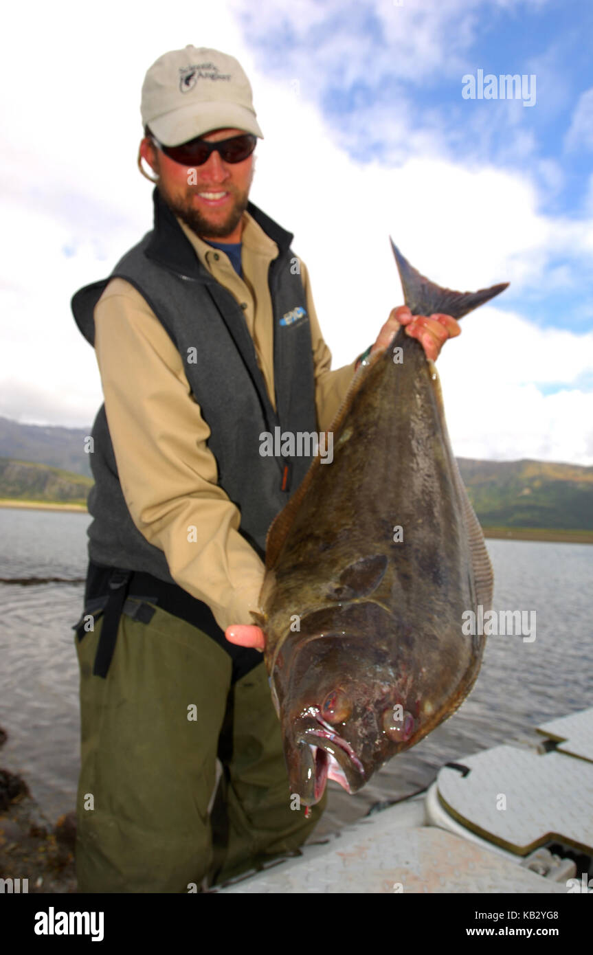 Fisherman holding a halibut caught while fishing in Alaska Stock Photo