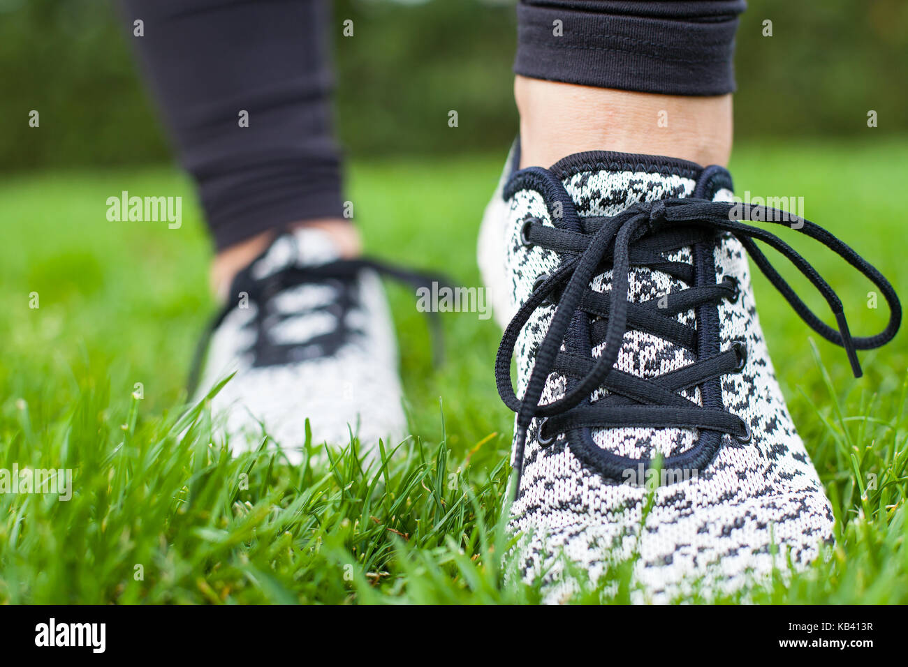 Close up sportive female training shoes on the green grass while doing