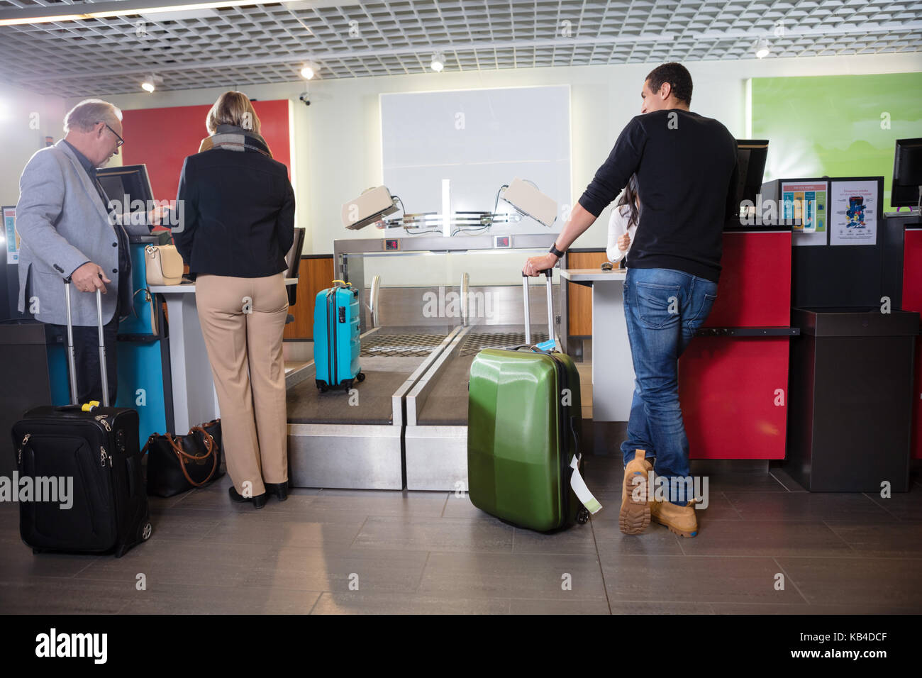 Male and female passengers with luggage at airport check-in desk Stock Photo