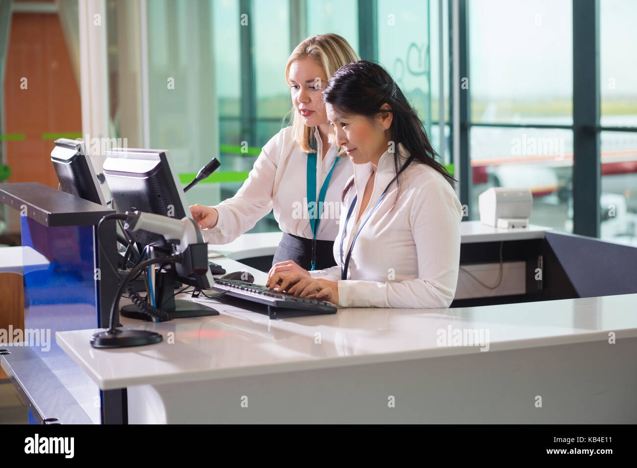 Multiethnic female ground staff using computer at counter in airport Stock Photo