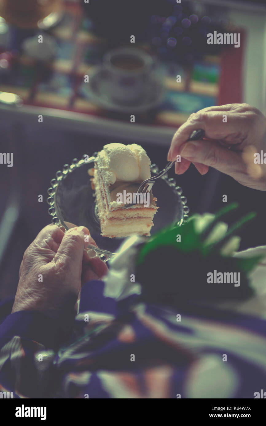 Senior female hands holding a cake and taking a piece Stock Photo