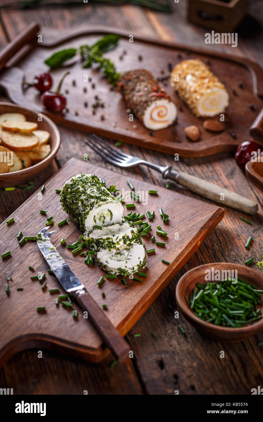 Cheese appetizer. Delicious soft cheese with fresh herbs served on a cutting board Stock Photo