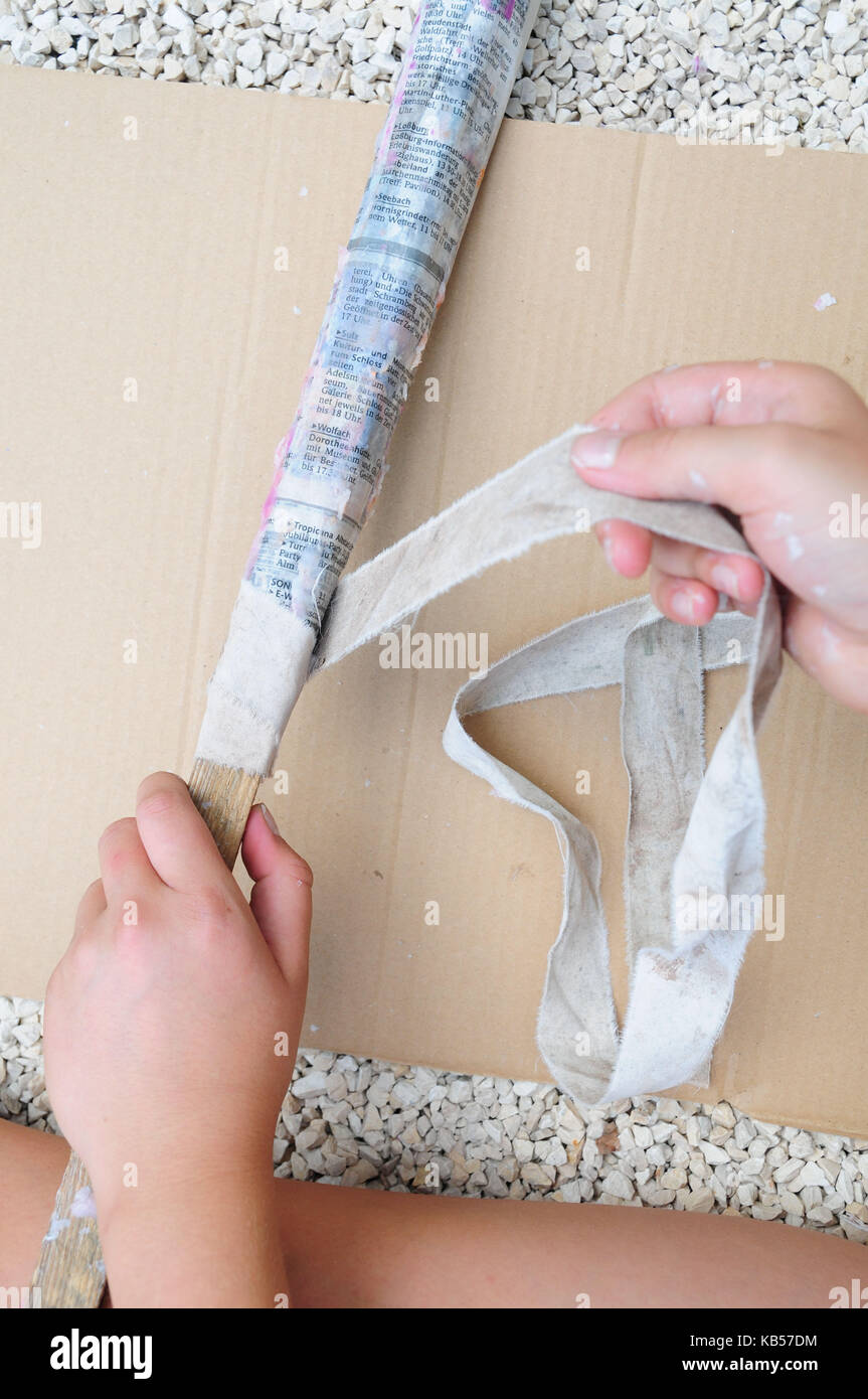 handicraft instruction, step by step, build torches by yourself, child hands wrap newspaper around wooden stick, picture series with text Stock Photo