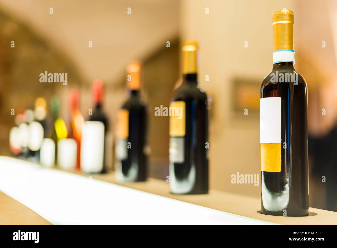 A shallow focus perspective view of a row of colorful Tuscany wine bottles on a shop shelf Stock Photo