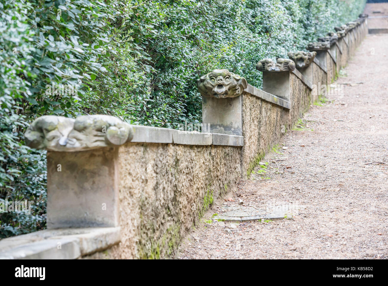 Shallow focus view of a water aqueduct decorated by scaring animal heads along the straight green alley at the Boboli gardens of Florence Stock Photo