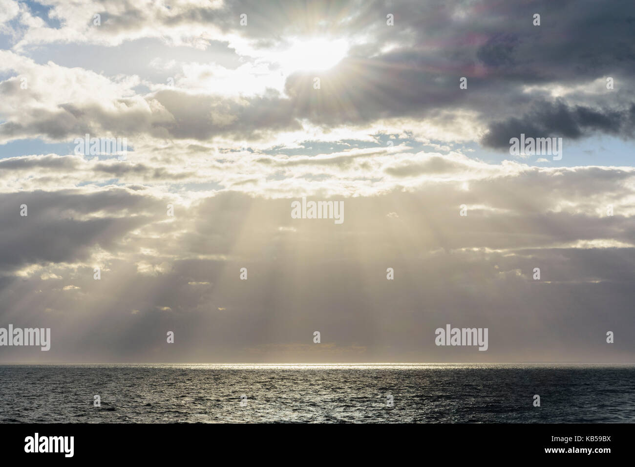 Sun breaks through the clouds with sunrays over sea, North Sea, United ...