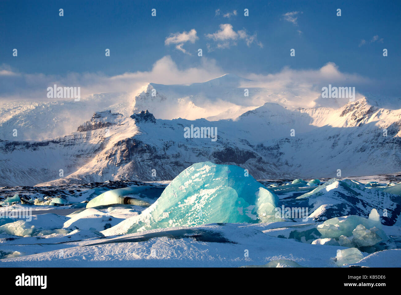 Winter view over frozen Jokulsarlon Glacier Lagoon showing blue icebergs covered in snow and distant mountains, South Iceland Stock Photo