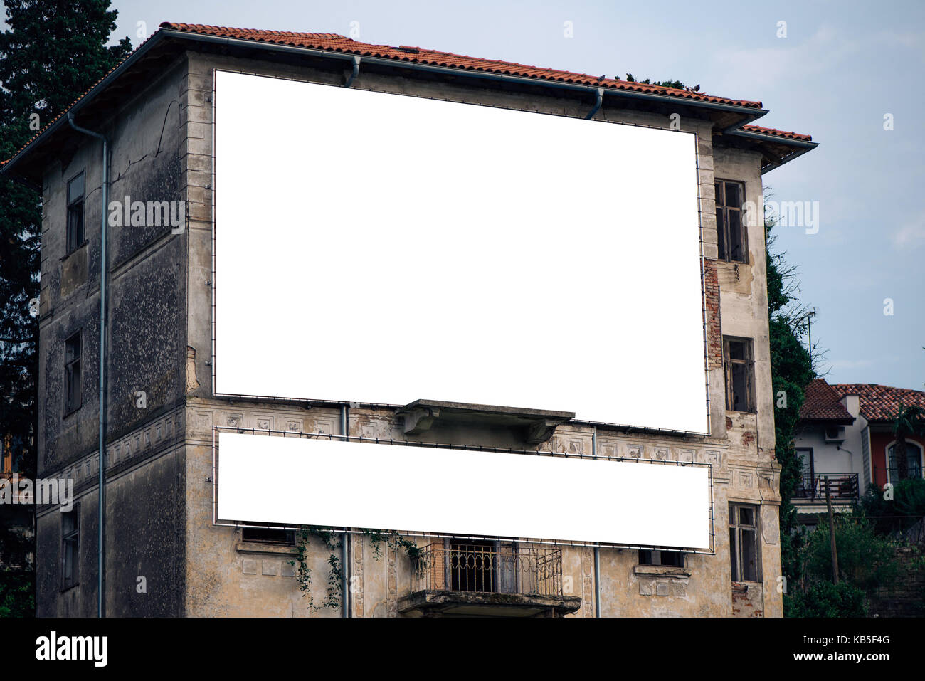Empty white advertisement billboard mock up copy space on old abandoned building facade, outdoor advertising blank space Stock Photo