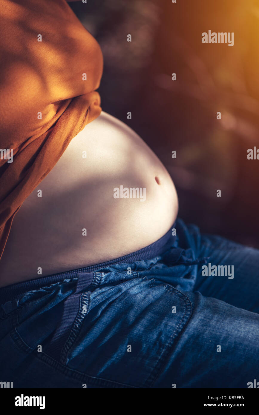 Pregnant woman relaxing and sunbathing belly on warm summer sunlight, selective focus Stock Photo