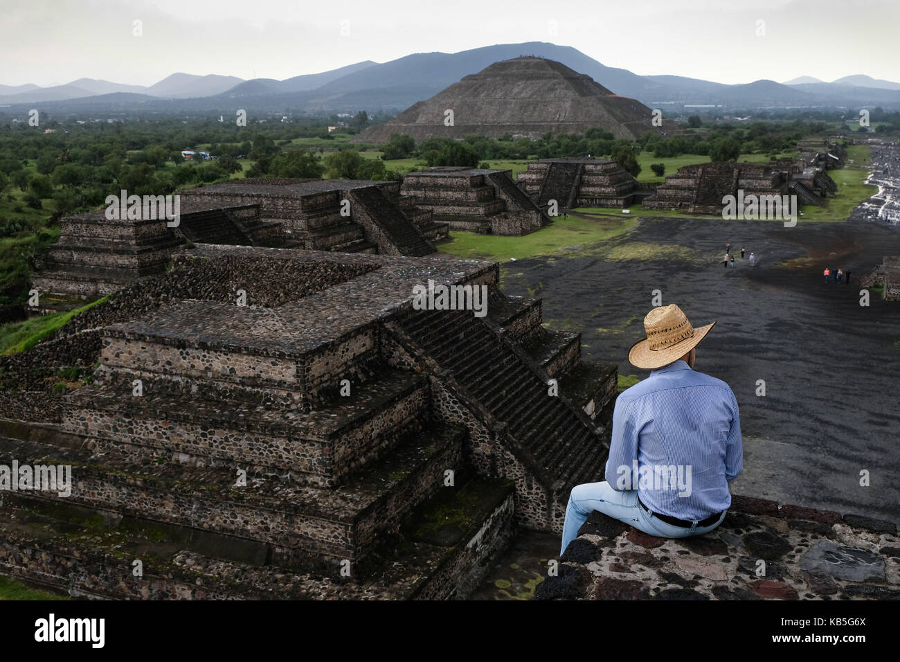 A man sits on a ledge looking over Teotihuacán, an ancient Mesoamerican city located in a sub-valley of the Valley of Mexico. Stock Photo