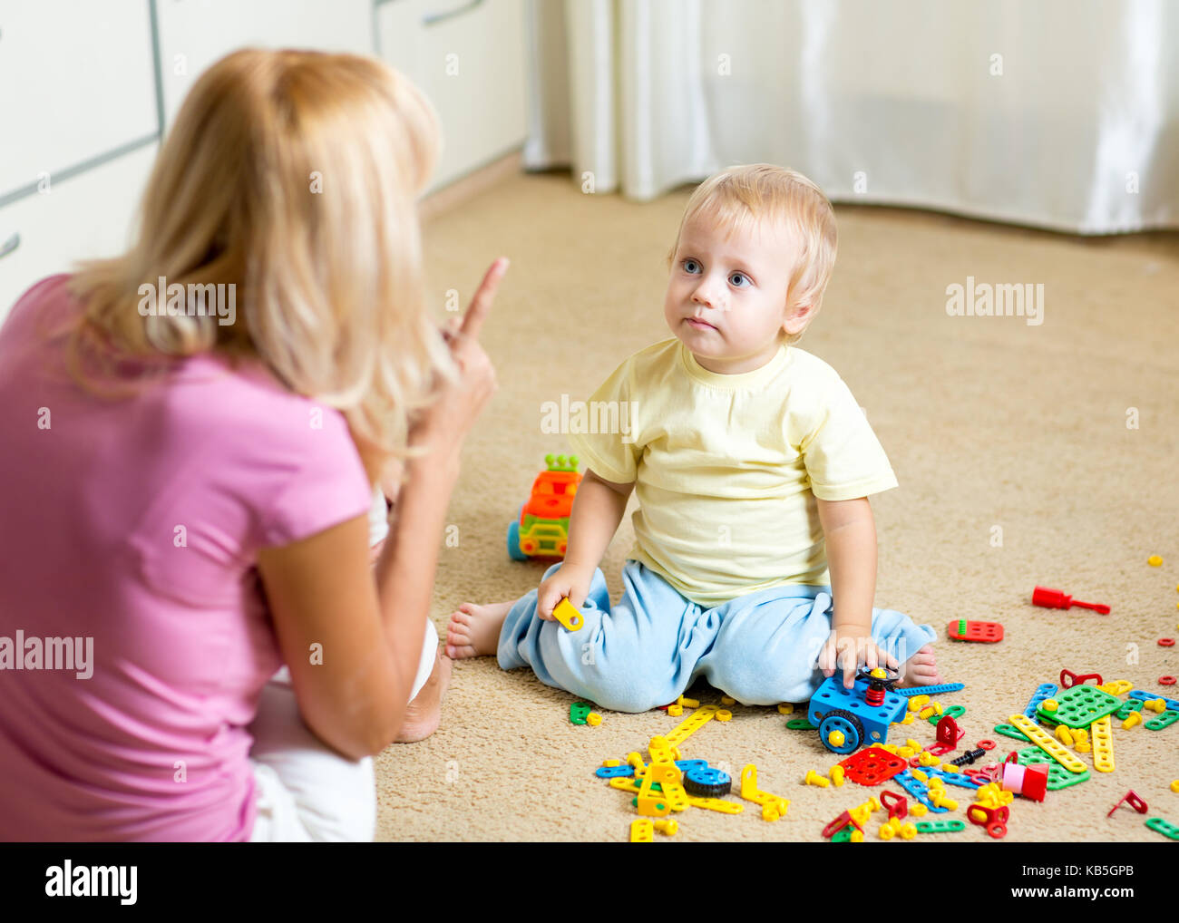 Mother scolding her little kid in jest at home Stock Photo