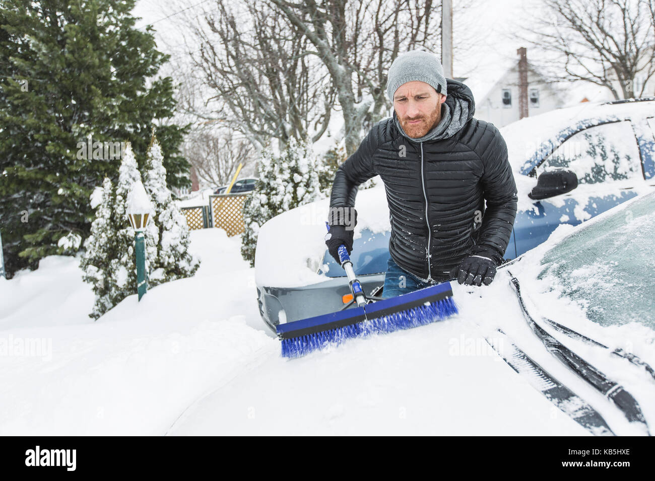 man brushing the snow off the windshield of his car Stock Photo