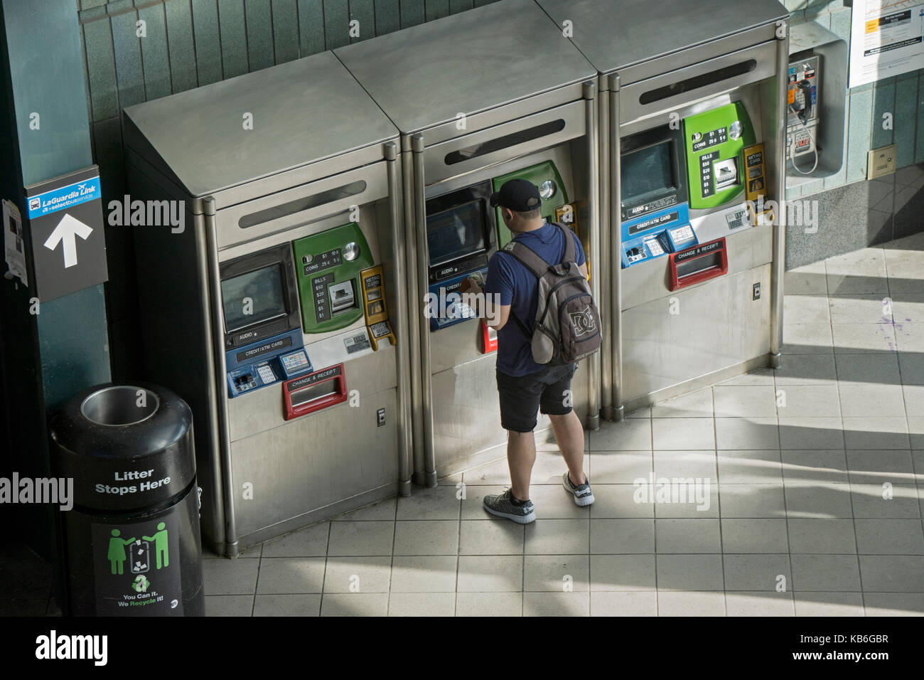 A young man with a backpack purchasing or refilling his Metrocard at the 74th Street Broadway station on the 7 line. In Jackson Heights, Queens, NYC Stock Photo