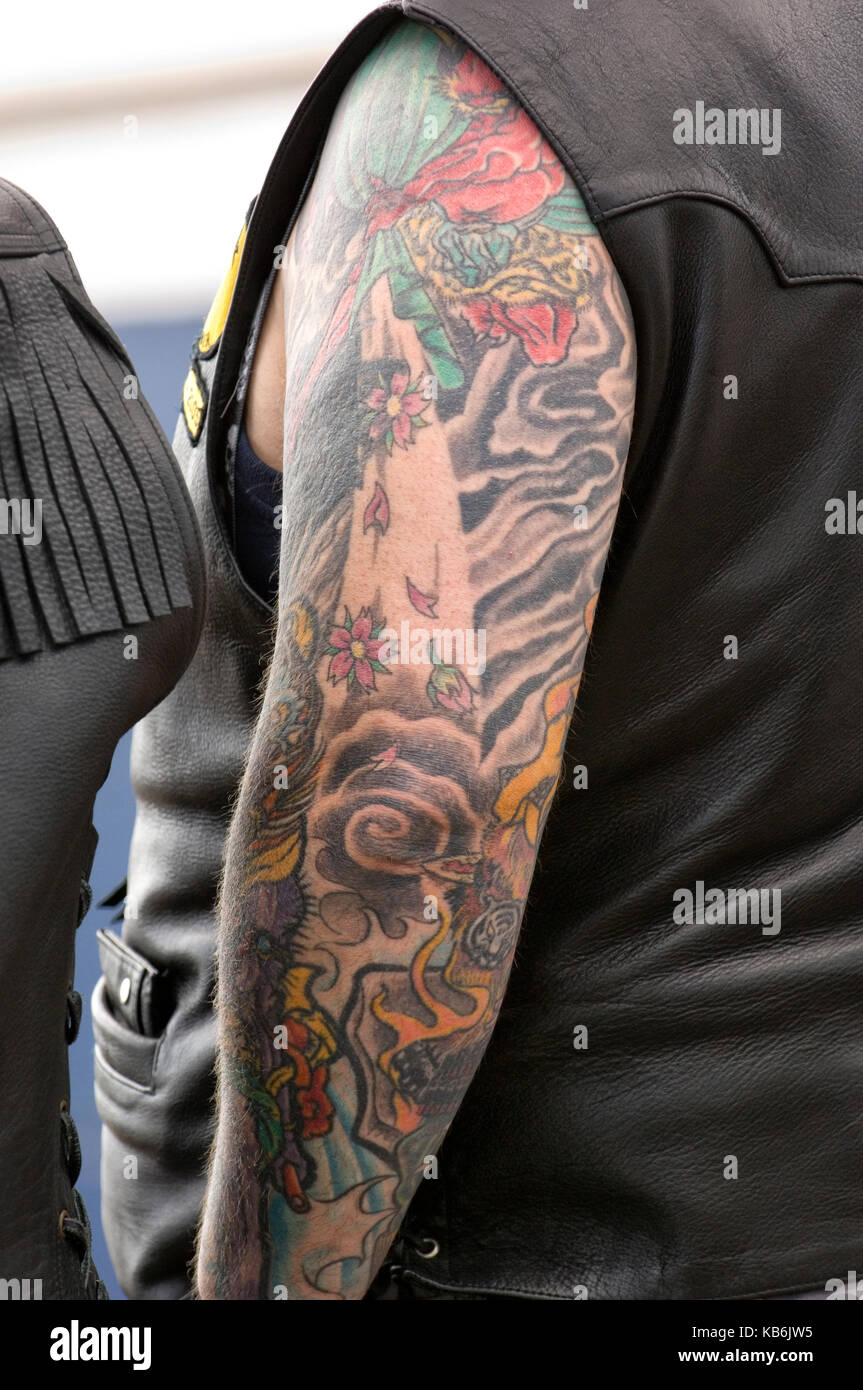Leather clad biker with left arm heavily tattooed - abstract, black, blue, red, green, orange. Stock Photo