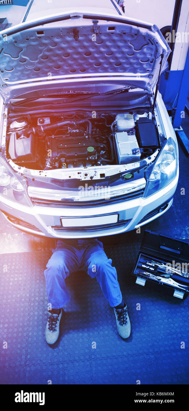 Mechanic lying and working under car at repair garage Stock Photo Alamy