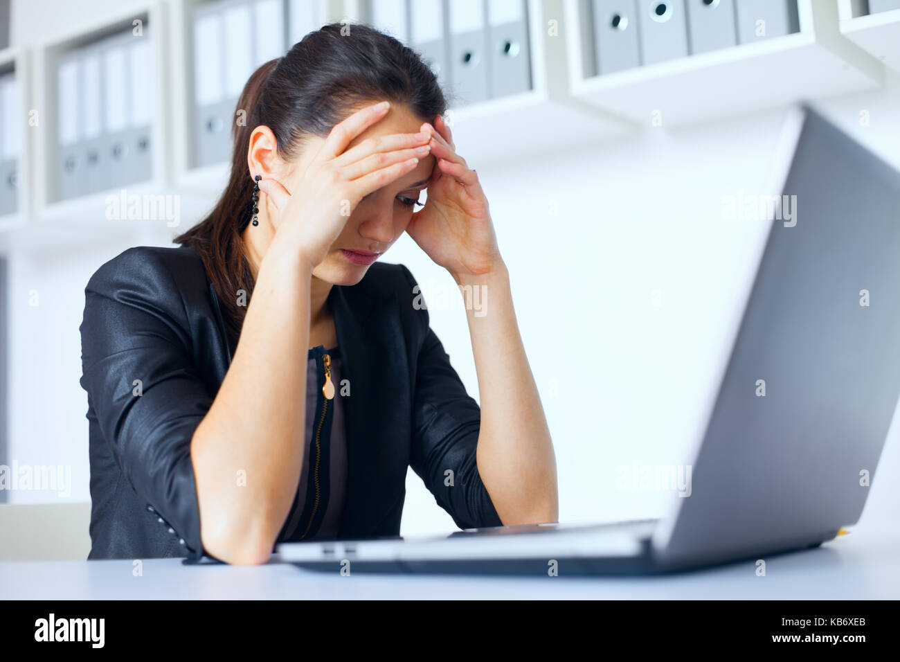 Portrait of tired young business woman with laptop at the office Stock ...
