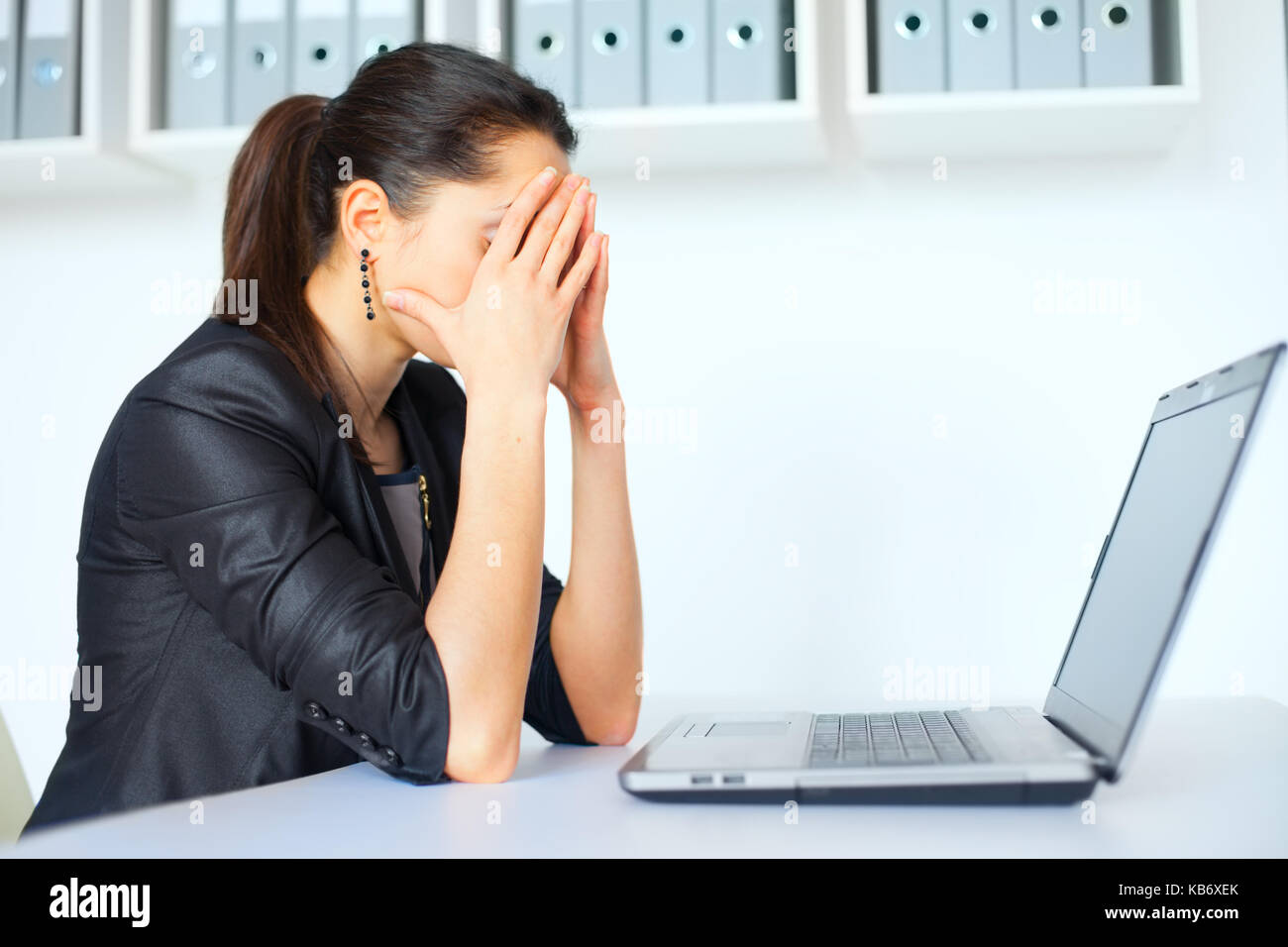 Portrait of tired young business woman with laptop at the office Stock ...
