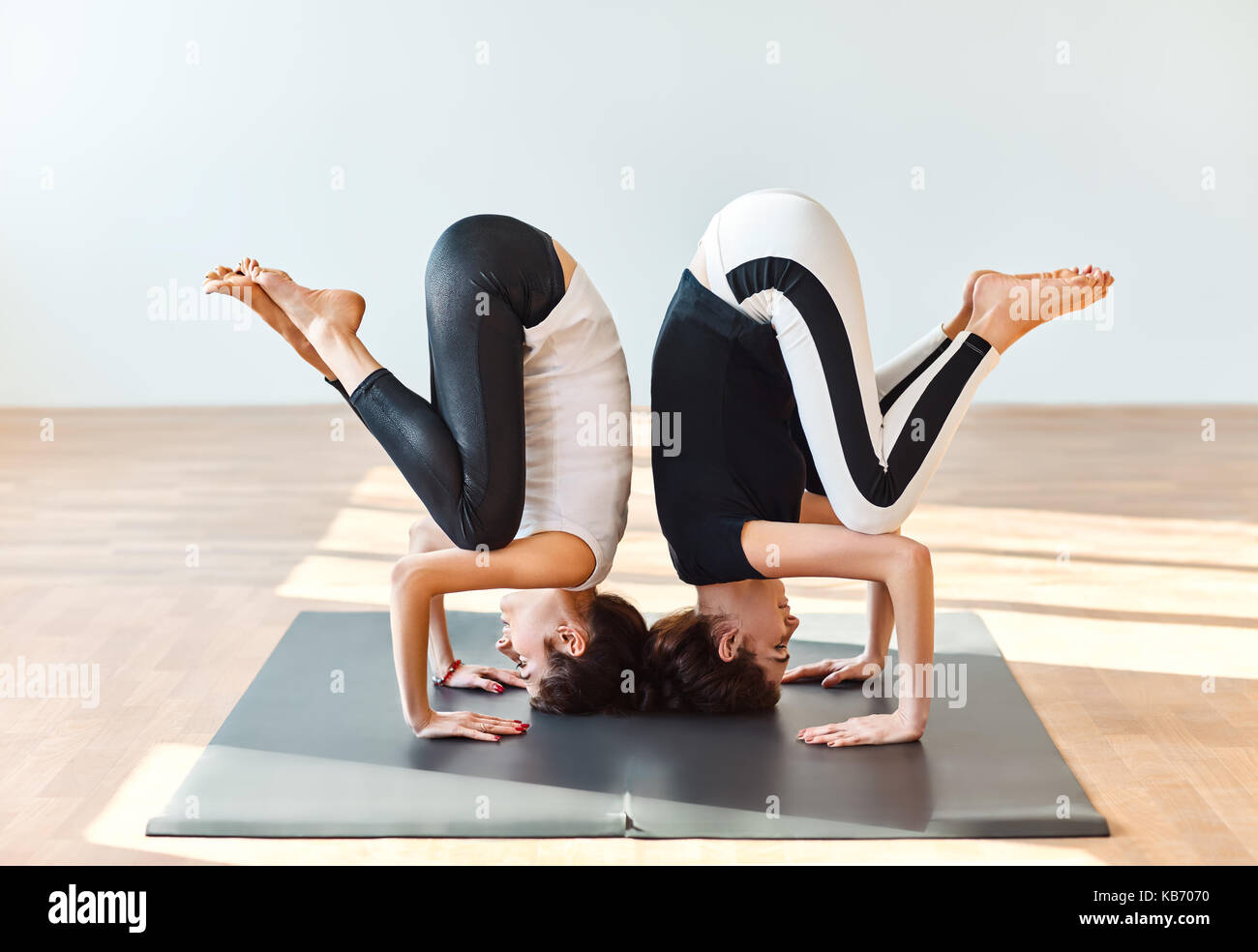 Two young women doing yoga asana crane pose. Bakasana Stock Photo