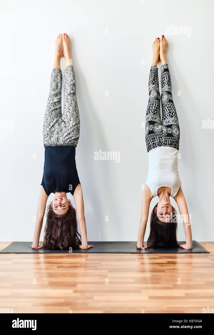 Two young women doing yoga handstand pose. Adho Mukha Vrksasana Stock Photo  - Alamy