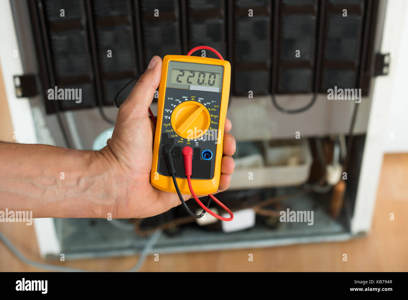 Cropped image of male repairman checking fridge with digital multimeter ...