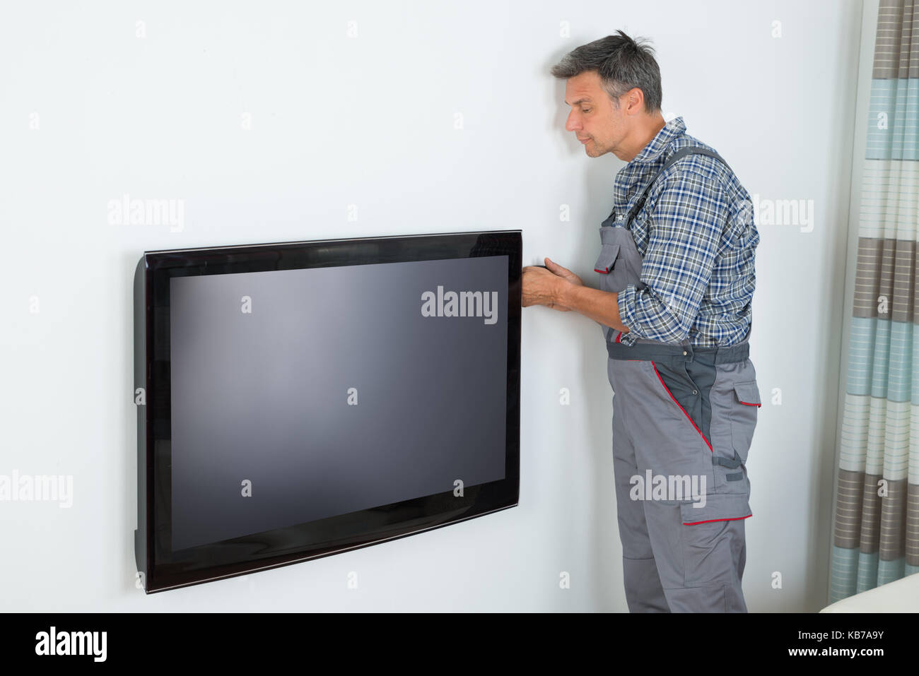 Side view of mature technician installing television at home Stock Photo
