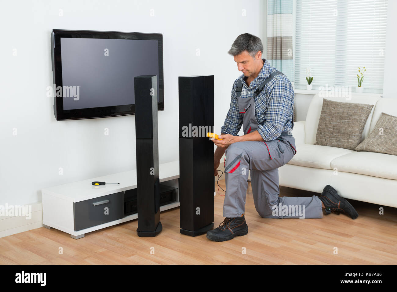 Full length of technician checking TV speaker with multimeter at home