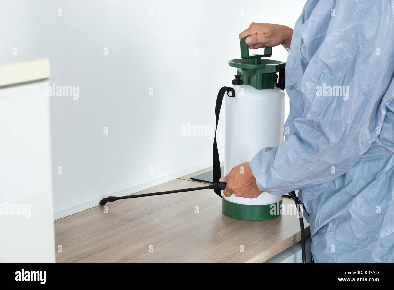 Midsection of exterminator spraying pesticide on kitchen counter Stock Photo