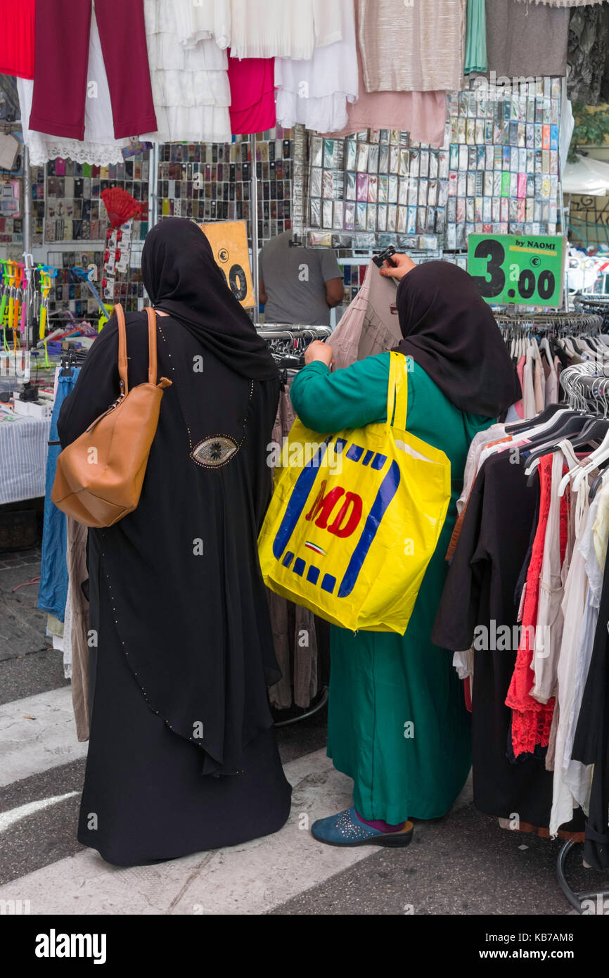 Muslim women shopping for bargain clothes in the market in Bologna, Italy. Stock Photo
