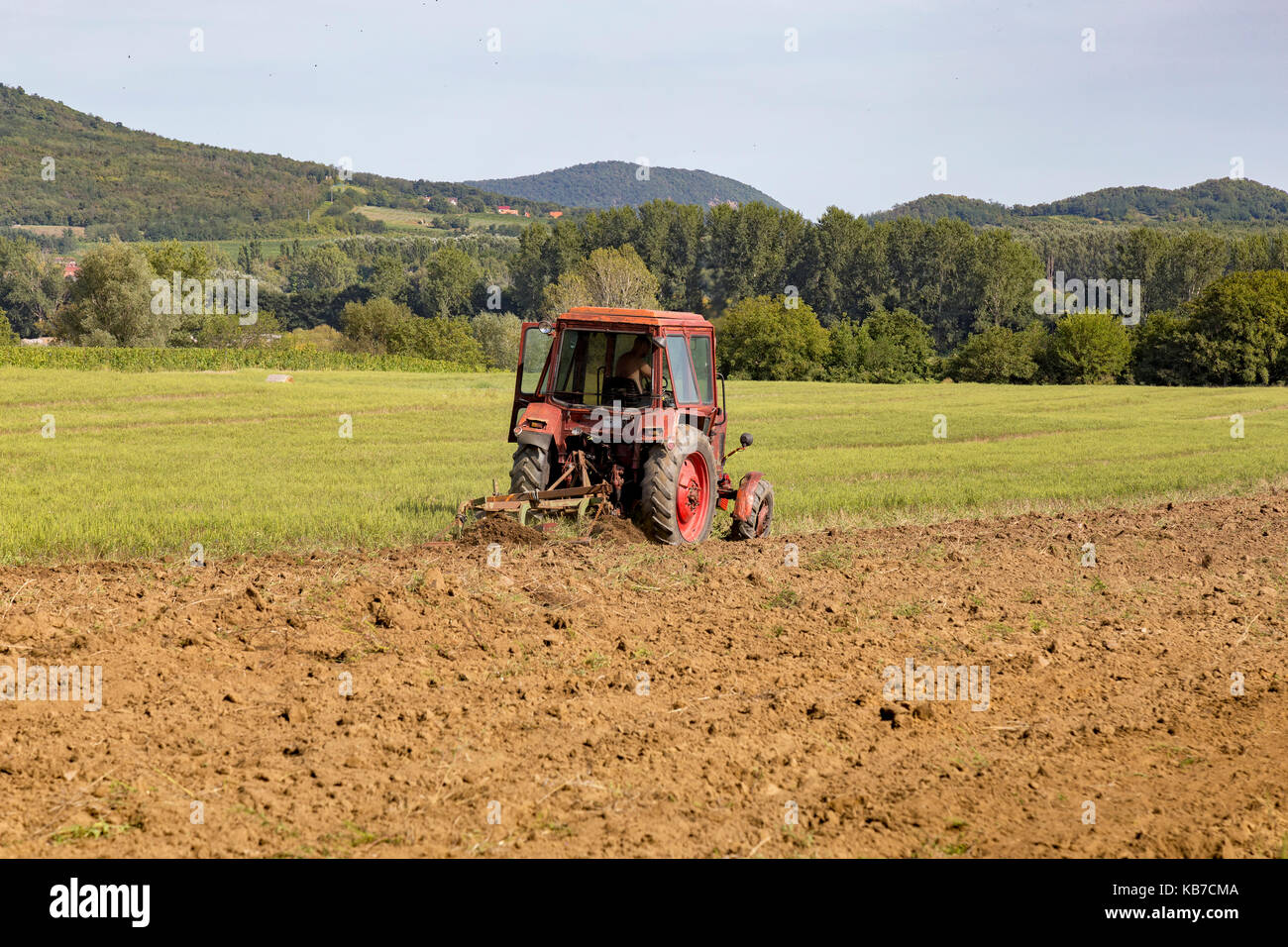 Old tractor working on the field Stock Photo - Alamy