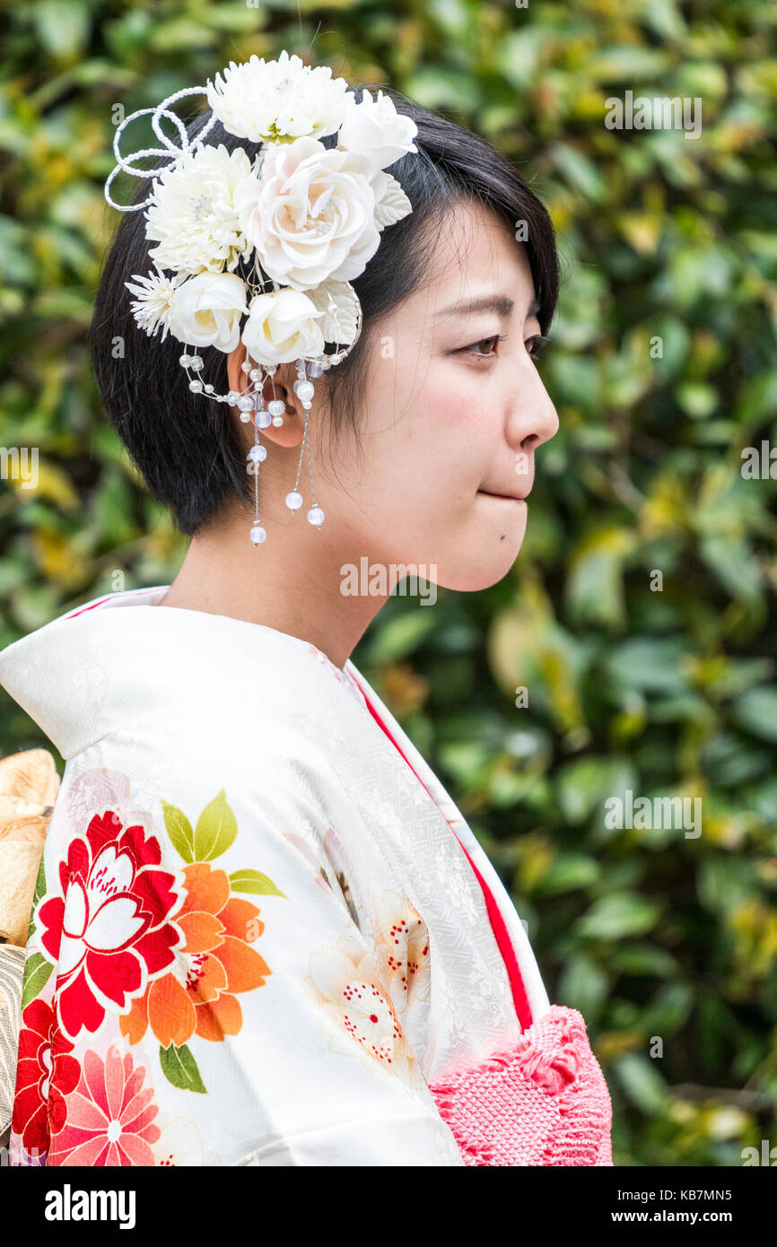 Japan. Head and shoulders side view of young Japanese woman in cream