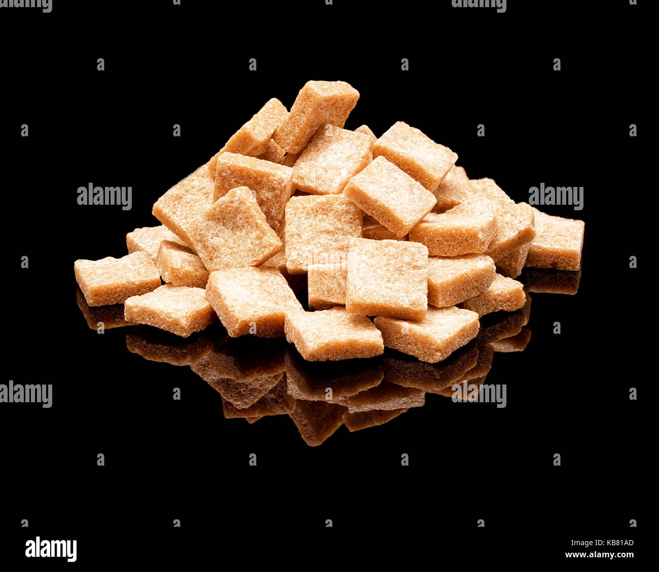 Pile of lumpy brown cane sugar with real reflection on a black glossy background Stock Photo