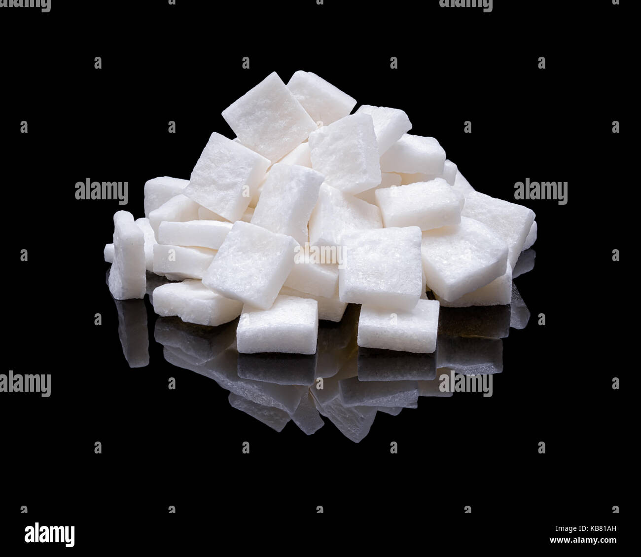 Pile of lumpy white cane sugar with real reflection on a black glossy background Stock Photo