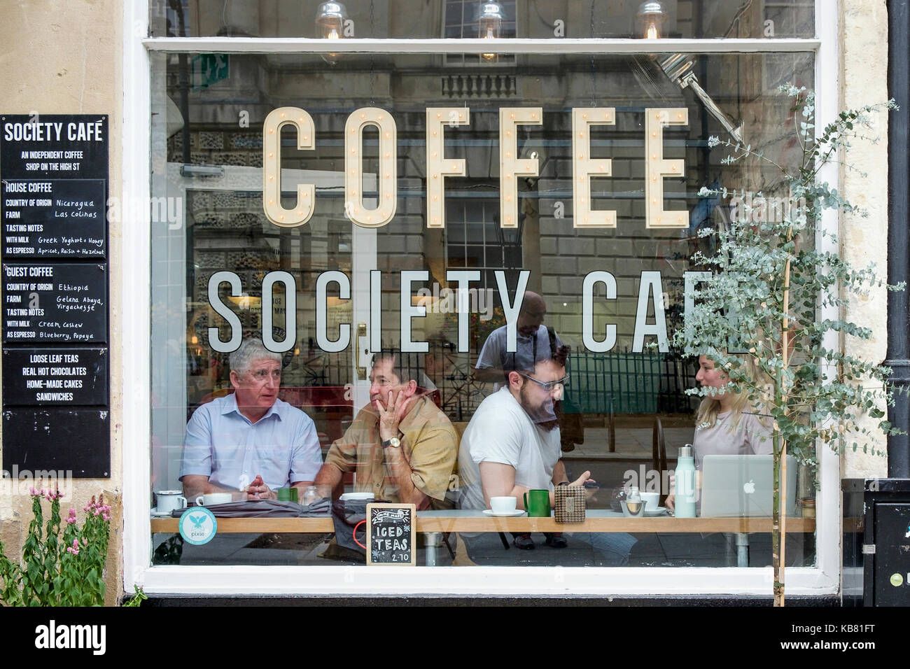 Customers drinking coffee are pictured sitting at the window of a Coffee society cafe /  bar shop in Bath, Somerset, England, UK Stock Photo