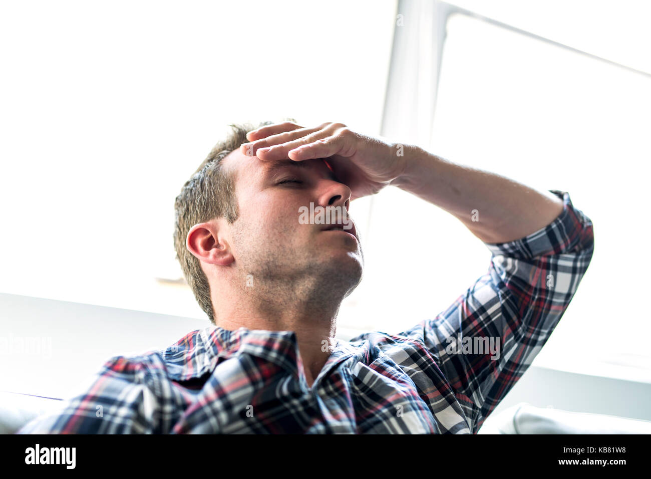 Young man suffering from headache at home Stock Photo - Alamy