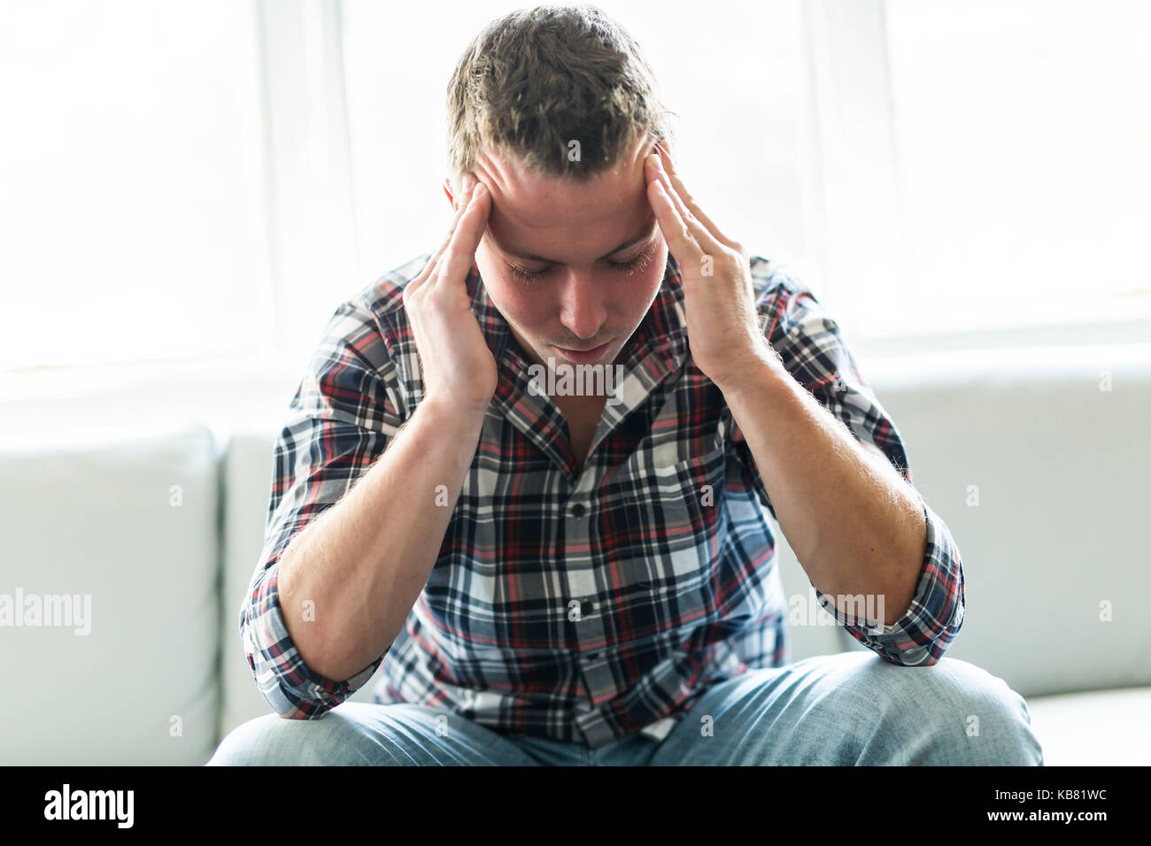 Young man suffering from headache at home Stock Photo - Alamy