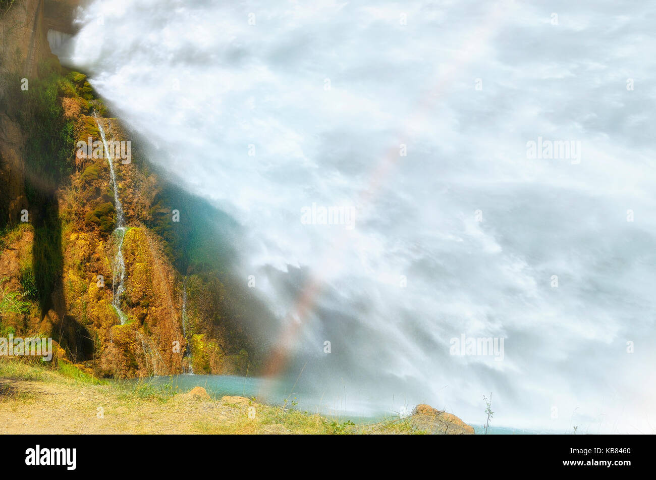 Big waterfall. Just under of the spillway, in a hydroelectric dam. Water flowing, strongly, towards the river. Beautiful colorful landscape. Rainbow Stock Photo