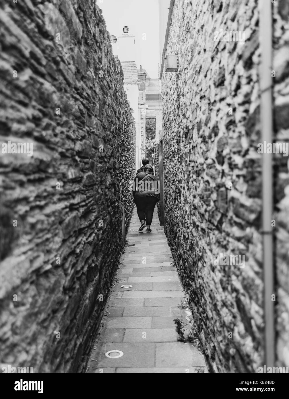 Narrow walkway, two people waking away Stock Photo