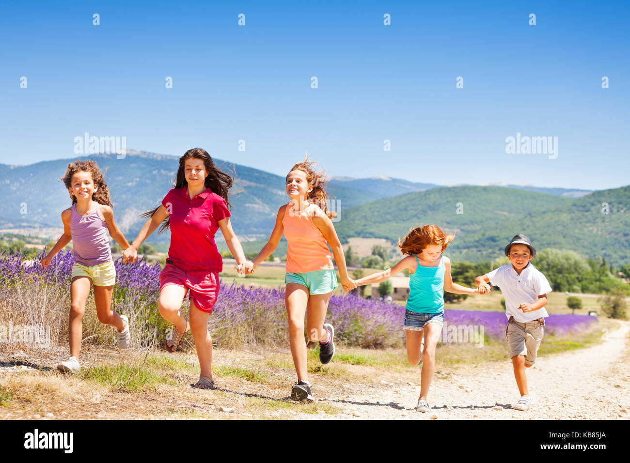 Happy kids running together through lavender field Stock Photo - Alamy