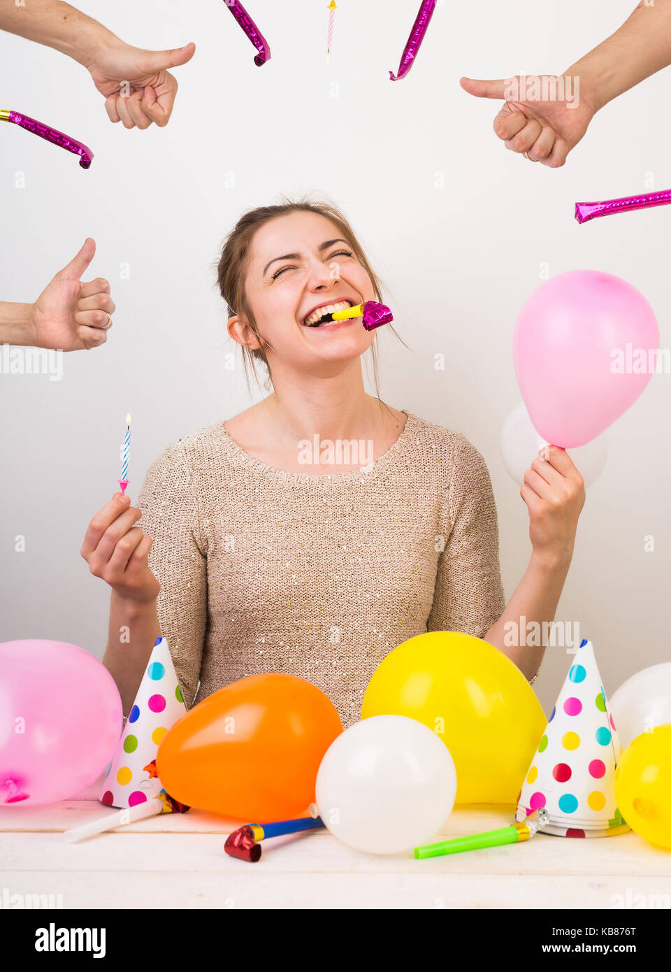 party, celebration, birthday concept. extremelly happy young girl is shrieking with laughter, holding small pink balloon in one arm, blue candle in ot Stock Photo