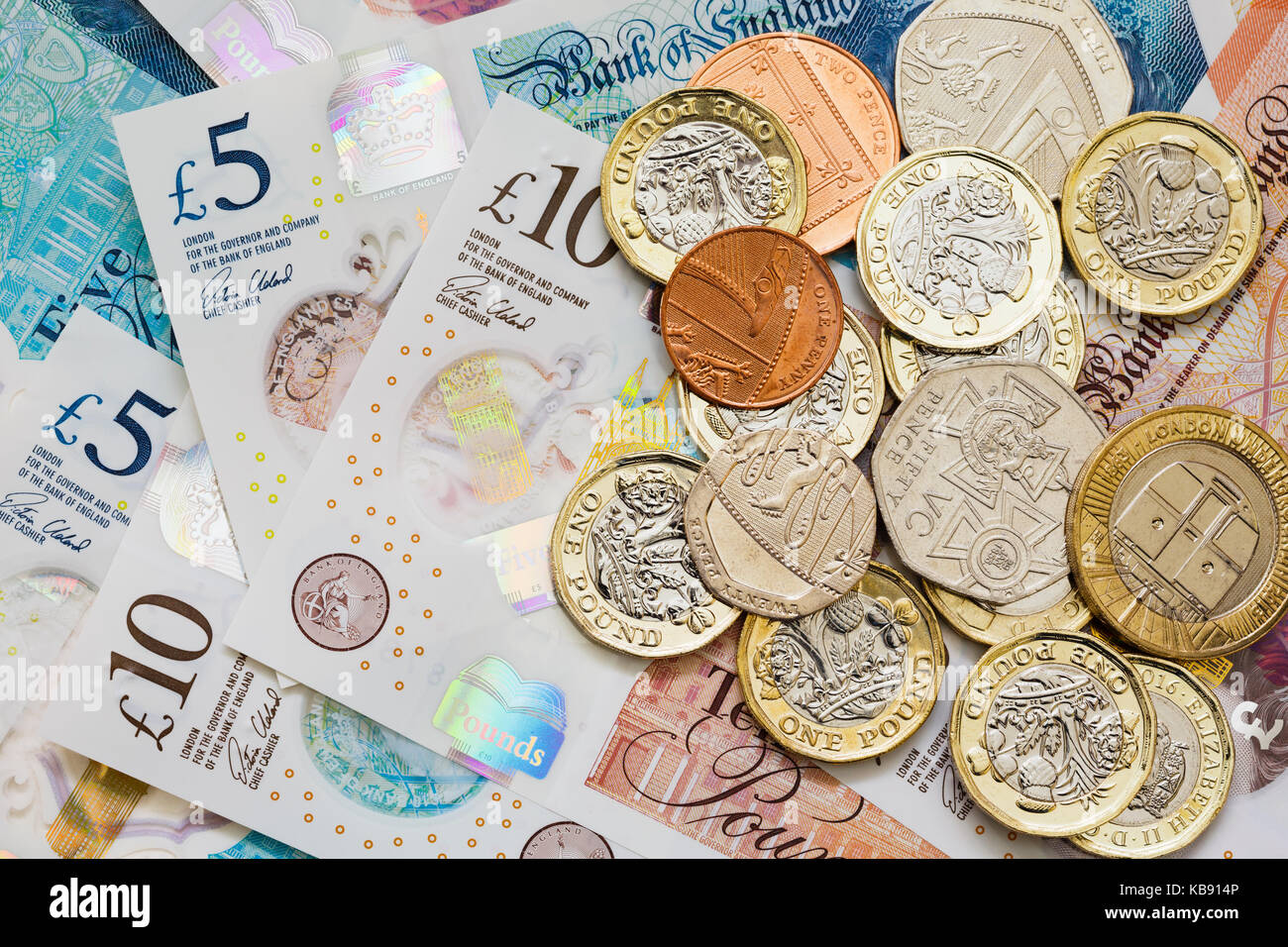 British UK money sterling £10 and £5 notes GBP and a pile of new issue pounds one pound coins cash. Saving money savings concept. England UK Britain Stock Photo