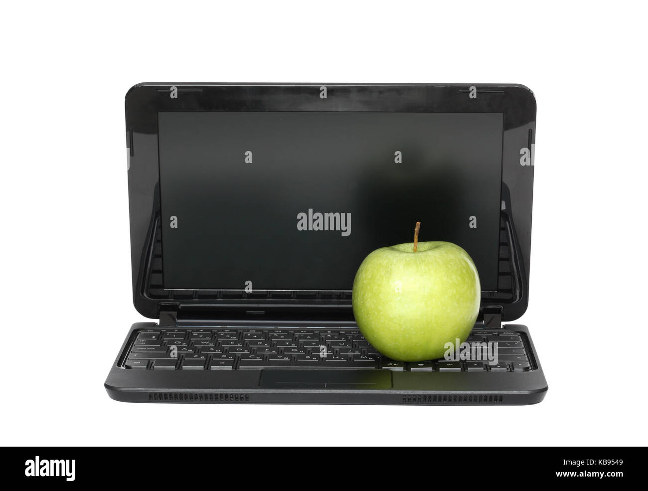 Green apple lying on black laptop. Isolated on white with clipping path ...