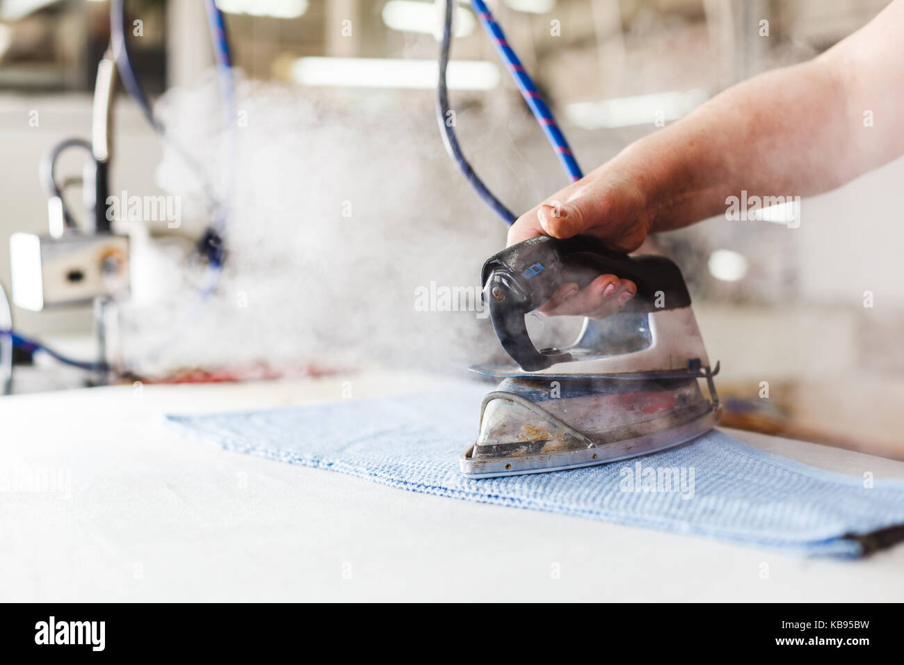 Professional ironing in dry cleaner detail of iron and hands. Presser