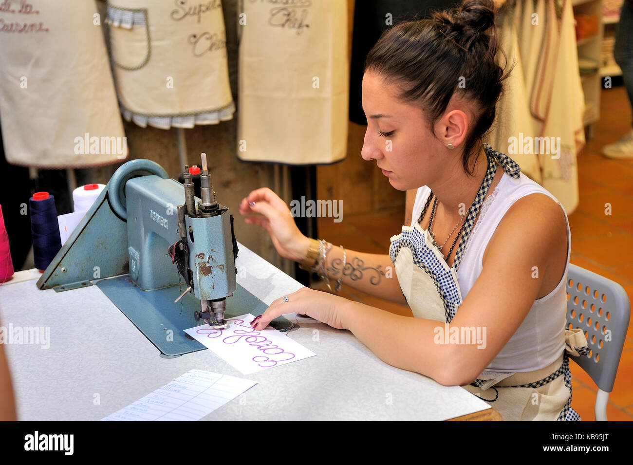 Young embroiderer realize custom embroideries in the center of the city of Carcassonne Stock Photo