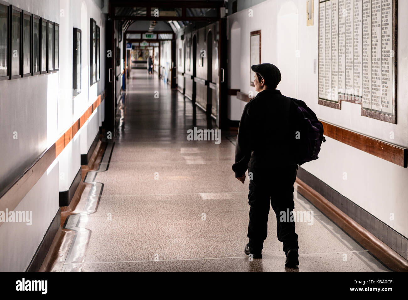 A man wearing a flat cap walks along the Victorian corridor in the Royal Victoria Hospital, Belfast. Stock Photo