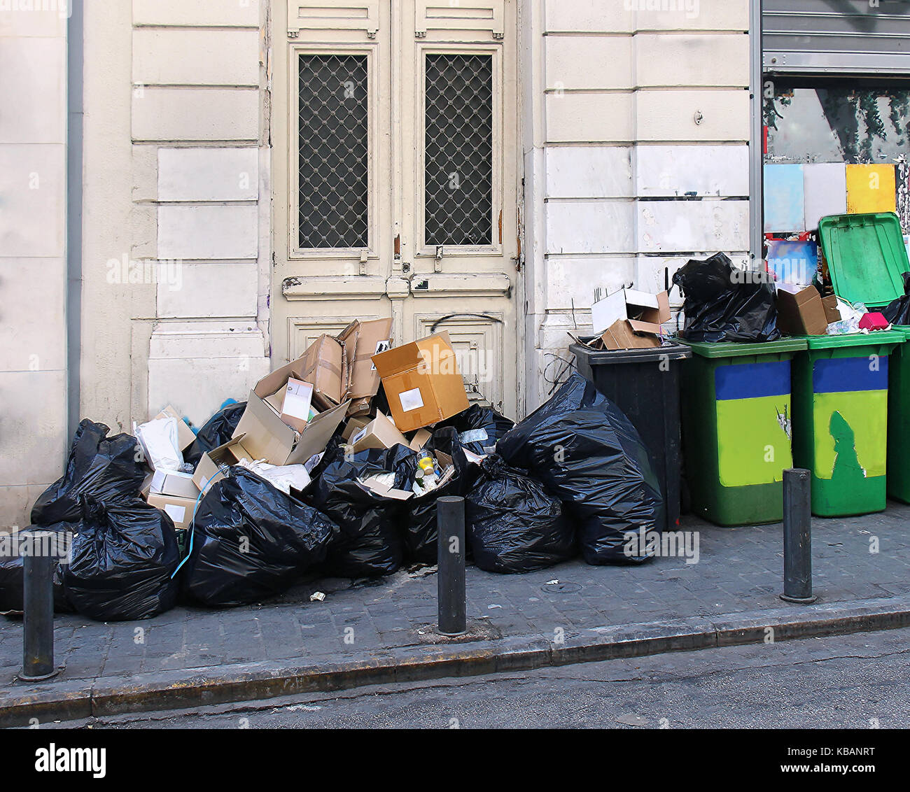 Large garbage pile inside black bags and green containers on street Stock Photo